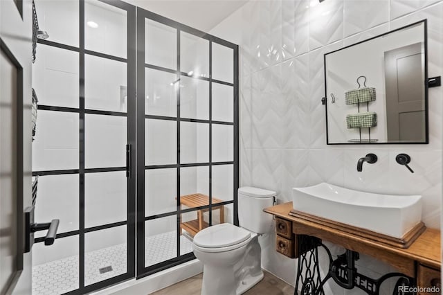 bathroom featuring tile walls, toilet, vanity, and a shower with door