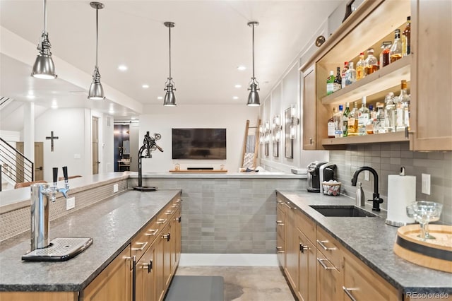 kitchen with hanging light fixtures, dark stone countertops, a kitchen island, and sink