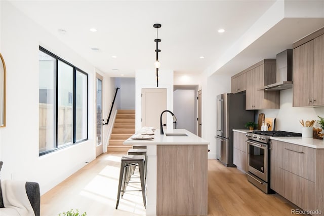 3433 Lawrence St Unit 1, Denver, CO 80205 - kitchen with wall chimney exhaust hood, appliances with stainless steel finishes, a sink, modern cabinets, and an island with sink