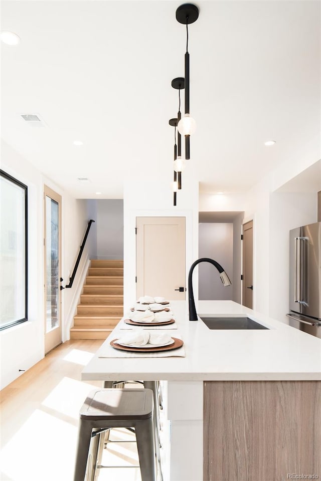 3433 Lawrence St Unit 1, Denver, CO 80205 - kitchen featuring a sink, light wood-style flooring, light countertops, a kitchen island with sink, and recessed lighting