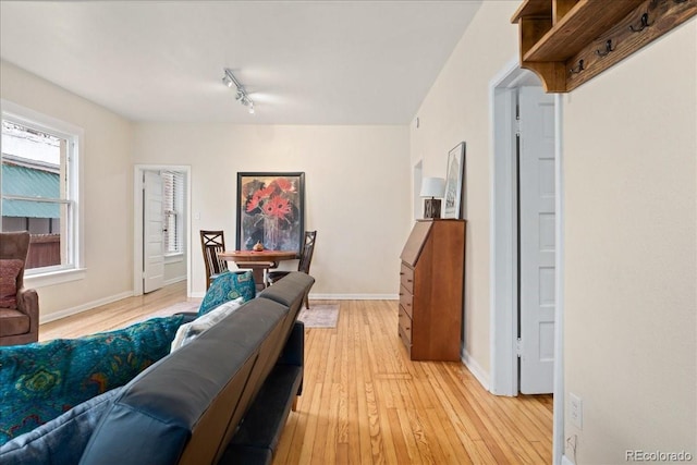 living area featuring light wood-type flooring, baseboards, and track lighting