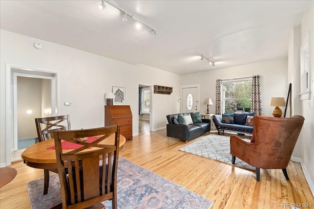 living room featuring rail lighting, wood finished floors, and baseboards