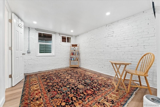 sitting room with brick wall, light wood finished floors, and recessed lighting