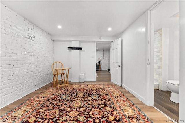 basement with light wood-style flooring, brick wall, recessed lighting, and baseboards