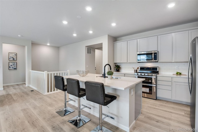 13351 E 100th Pl, Commerce City, CO 80022 - kitchen featuring decorative backsplash, appliances with stainless steel finishes, a center island with sink, a sink, and a breakfast bar