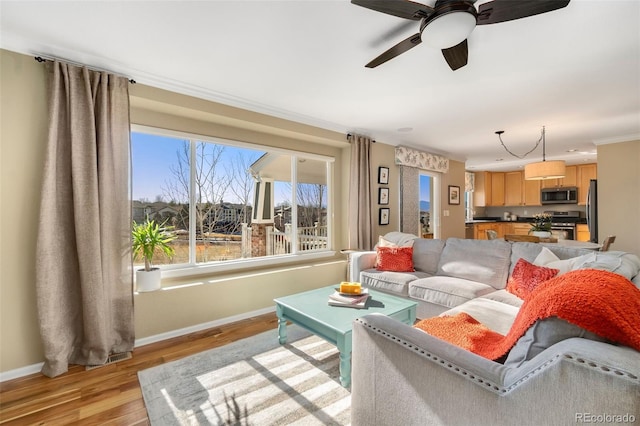 living room with ceiling fan, crown molding, and light wood-type flooring