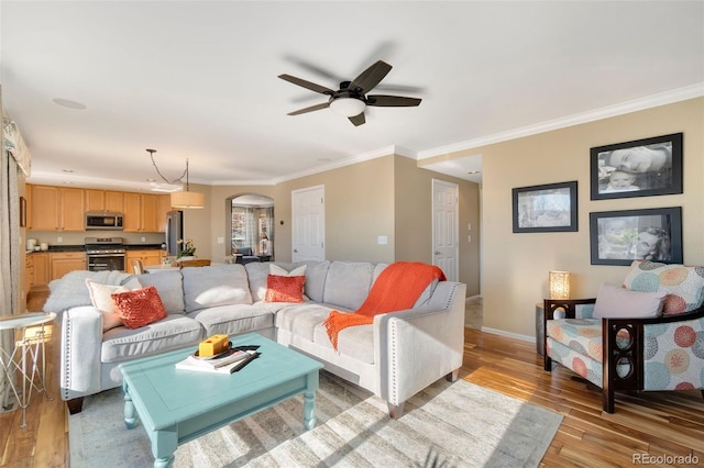 living room with ceiling fan, crown molding, and light hardwood / wood-style flooring