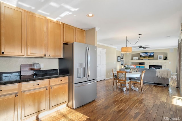 kitchen with ceiling fan, a tiled fireplace, ornamental molding, light brown cabinetry, and stainless steel fridge