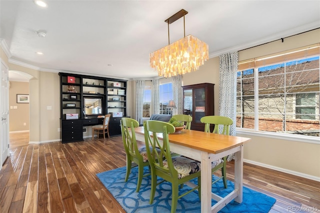 dining space with dark hardwood / wood-style floors, an inviting chandelier, and ornamental molding