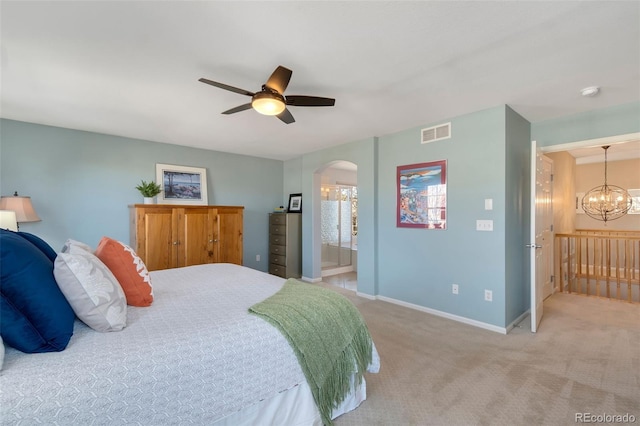 bedroom featuring light carpet, ensuite bath, and ceiling fan with notable chandelier