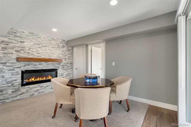 dining space with hardwood / wood-style floors and a tile fireplace