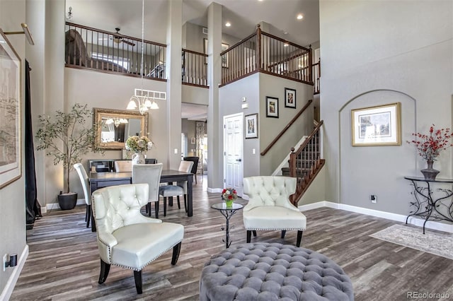 living room featuring an inviting chandelier, a towering ceiling, and dark hardwood / wood-style floors