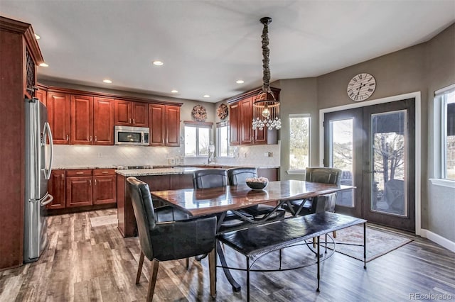 interior space with hardwood / wood-style floors, stainless steel appliances, french doors, a kitchen island, and decorative light fixtures