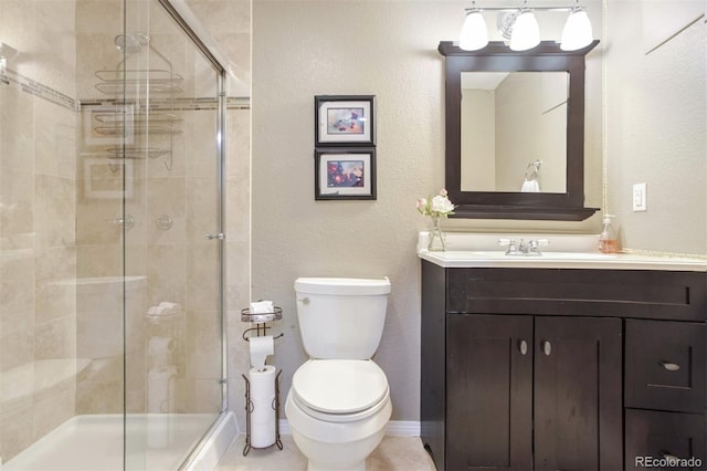 bathroom featuring toilet, vanity, and a shower with shower door