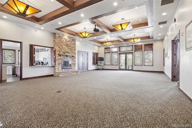 unfurnished living room featuring coffered ceiling, carpet floors, beamed ceiling, a fireplace, and a high ceiling