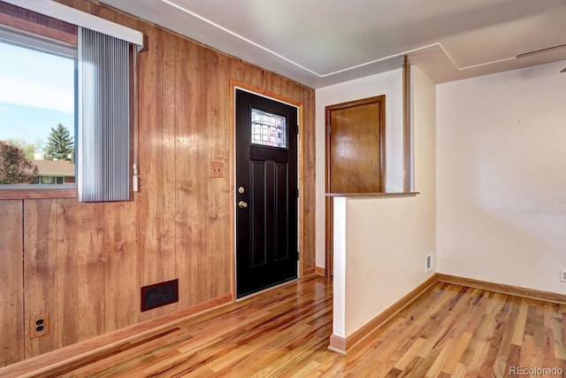 entrance foyer with light hardwood / wood-style flooring and wood walls