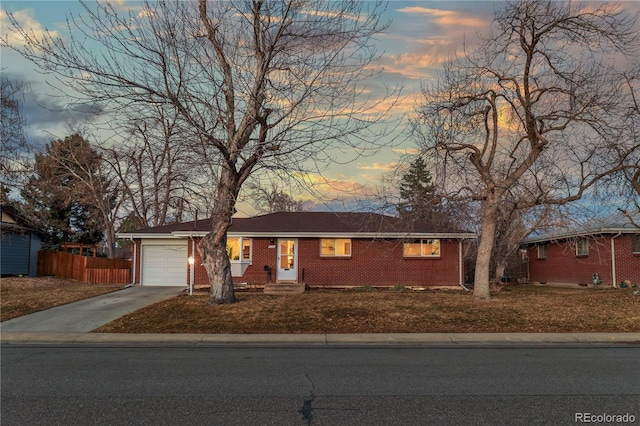 single story home featuring a garage, brick siding, fence, and driveway