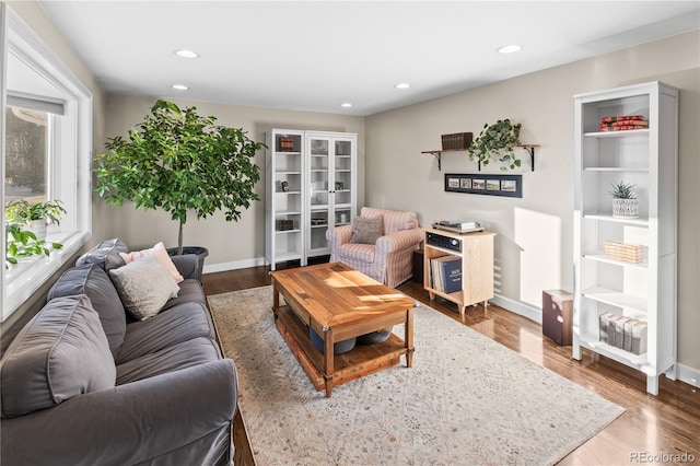 living area with baseboards, wood finished floors, and recessed lighting