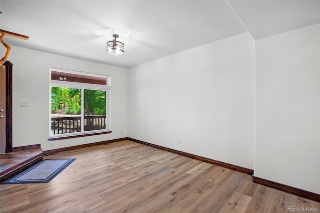 spare room with light hardwood / wood-style floors and a textured ceiling