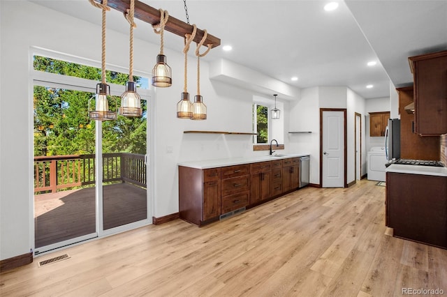 kitchen with dishwasher, light hardwood / wood-style floors, sink, and washer / dryer