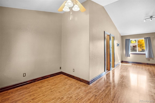 empty room with lofted ceiling, ceiling fan, and hardwood / wood-style floors