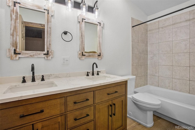 full bathroom featuring tiled shower / bath combo, vanity, toilet, and hardwood / wood-style flooring