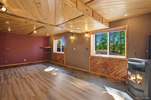 interior space with wood-type flooring, beamed ceiling, a wood stove, and wooden ceiling