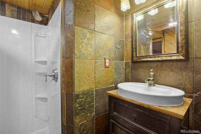 bathroom with walk in shower, vanity, and tile walls