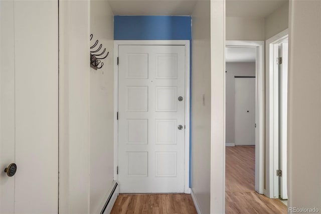 hall featuring a baseboard heating unit, light wood-type flooring, and baseboards