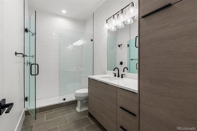 bathroom with vanity, a shower with door, and toilet