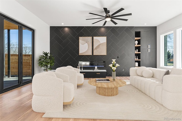 living room with ceiling fan, wood-type flooring, and tile walls