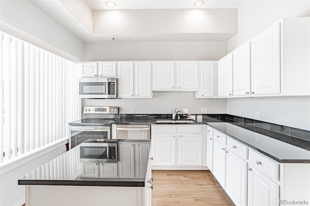 kitchen featuring sink, light hardwood / wood-style flooring, stainless steel appliances, white cabinets, and a kitchen island