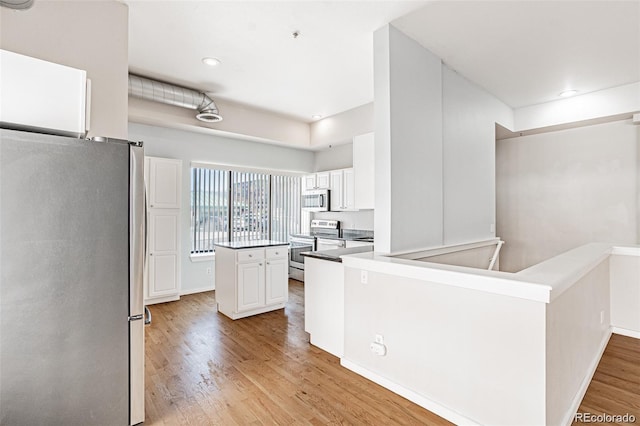 kitchen featuring white cabinetry, appliances with stainless steel finishes, kitchen peninsula, and light hardwood / wood-style flooring