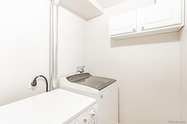 clothes washing area with cabinets and washing machine and dryer