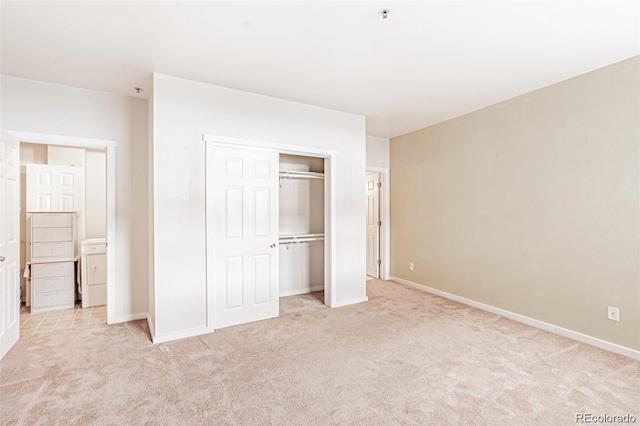 unfurnished bedroom featuring washer / clothes dryer, light carpet, and a closet