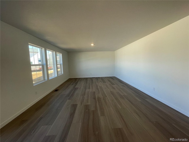 empty room with visible vents, baseboards, and dark wood-style flooring