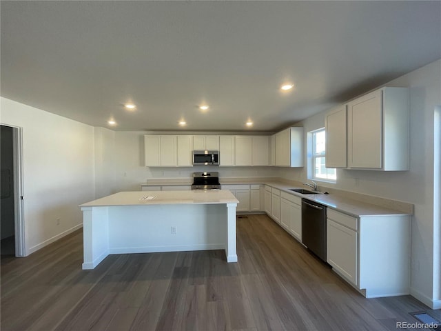 kitchen featuring a sink, a kitchen island, stainless steel appliances, white cabinetry, and dark wood-style flooring