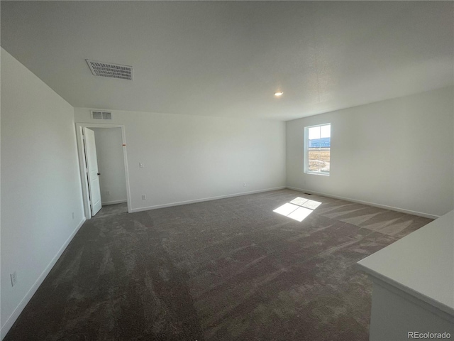 spare room with baseboards, visible vents, and dark colored carpet