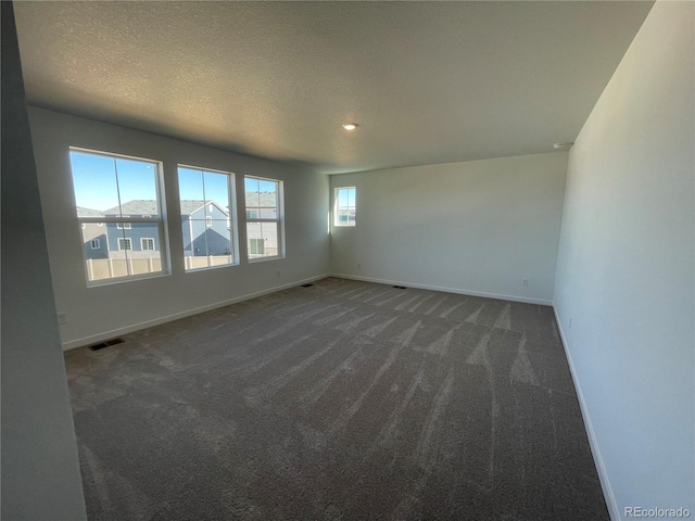 spare room featuring visible vents, baseboards, carpet floors, and a textured ceiling