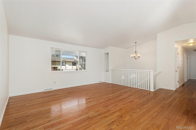 spare room with lofted ceiling, light wood-style floors, visible vents, and a chandelier