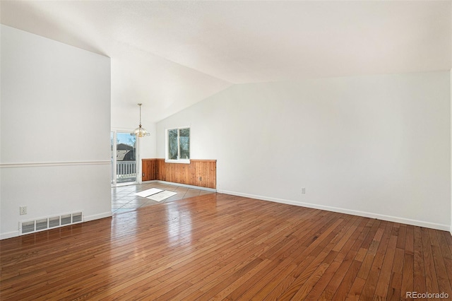 unfurnished room with a chandelier, visible vents, vaulted ceiling, and hardwood / wood-style floors