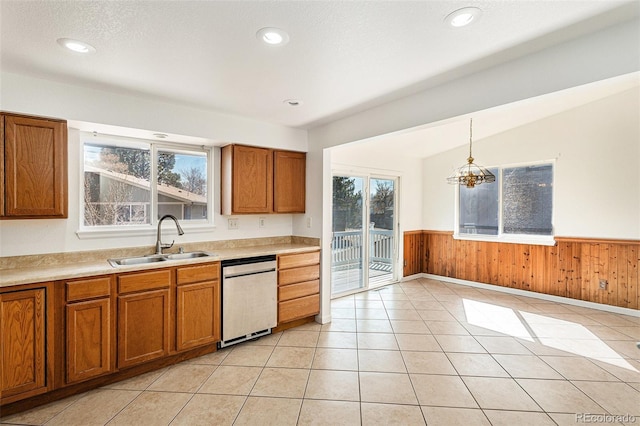 kitchen featuring dishwasher, wainscoting, a sink, and brown cabinets