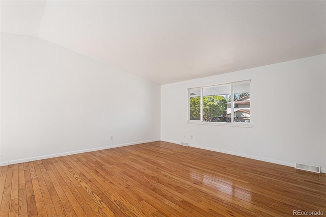 spare room featuring hardwood / wood-style flooring, visible vents, and baseboards