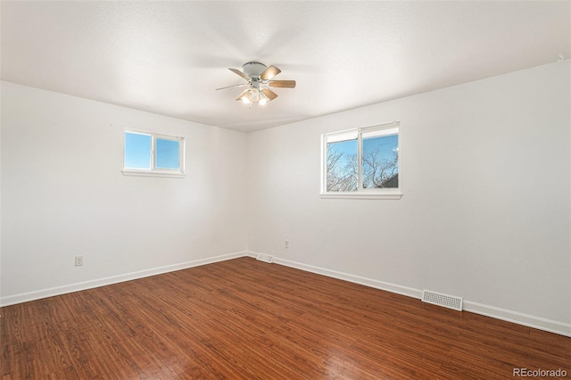 unfurnished room featuring wood finished floors, visible vents, and baseboards