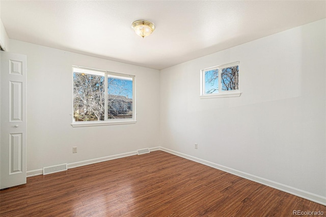 empty room with a healthy amount of sunlight, visible vents, and wood finished floors