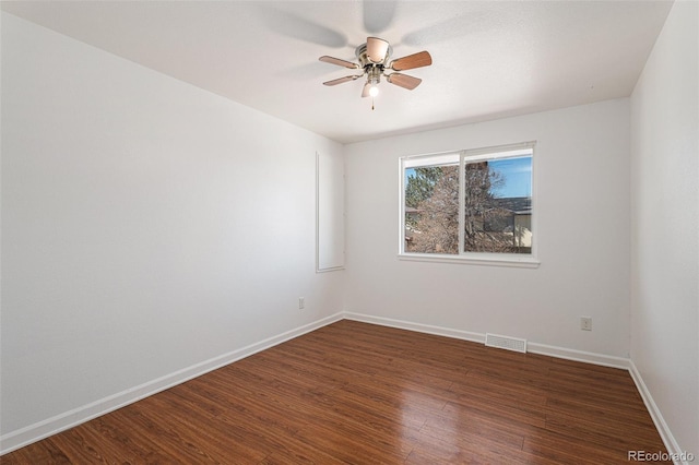 spare room featuring a ceiling fan, visible vents, baseboards, and wood finished floors