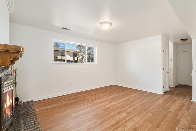 unfurnished living room with light wood-style flooring, visible vents, and baseboards