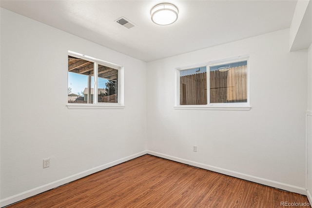 empty room with baseboards, visible vents, and wood finished floors