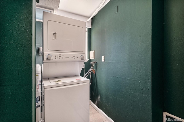 clothes washing area featuring laundry area, a textured wall, and stacked washing maching and dryer