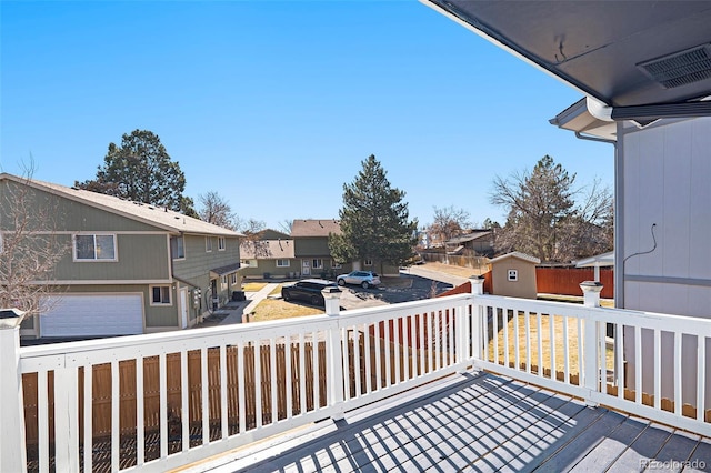 wooden terrace featuring a residential view, visible vents, an outbuilding, and a storage unit